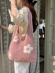 Detail der rosa gestrickten Netztasche mit weißem Blumenmuster an einer Frau getragen