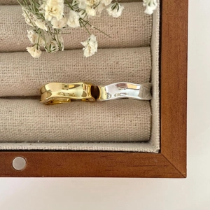 Macro view of gold and silver wavy irregular stackable rings in a beige velvet jewelry box