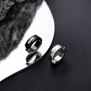 Minimalist silver and black metal ear clips with BHG lettering on leather background