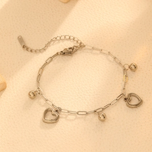 Close-up of stainless steel heart charms and metal beads on a silver chain link bracelet