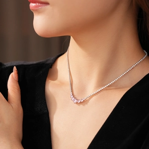 Close-up of minimalist silver necklace with pink zircon pendant on female model neck