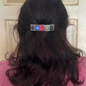 Miniature colorful book hair clip accessory styled on dark wavy hair for women