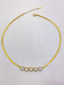 Detail of gold snake chain necklace featuring five white pearls and adjustable lobster clasp