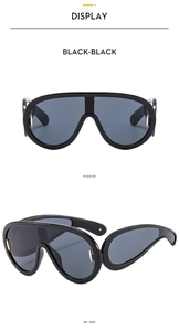 Front and 45-degree side view of black oversized sports sunglasses with gold metal trim