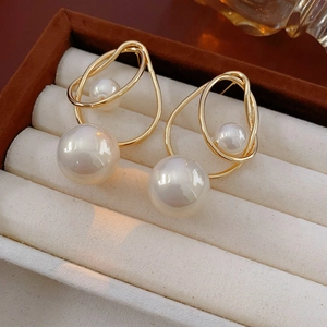 Macro detail of irregular gold geometric earrings with pearls on brown velvet tray