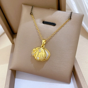 Dettaglio collana con conchiglia dorata e cristalli su una scatola per gioielli in pelle