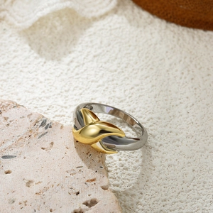 Detail of minimalist 18K gold and silver two-tone layered ring on natural stone surface