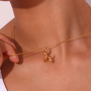 Close-up of golden balloon dog pendant necklace worn to show elegant fit and chain length