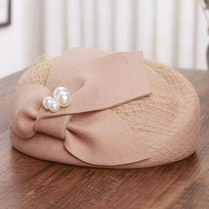 Close-up of pink wool pillbox hat featuring delicate mesh veil and pearl-studded bow
