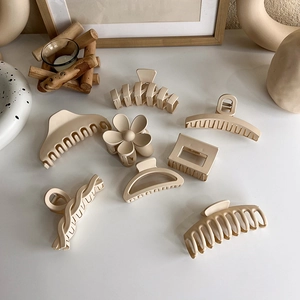 Detailed view of eight matte milk tea beige hair claws in various geometric shapes