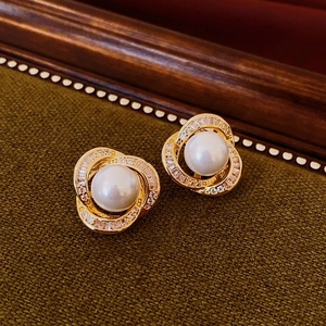 Macro shot of elegant pearl stud earrings with gold base and sparkling zircon accents