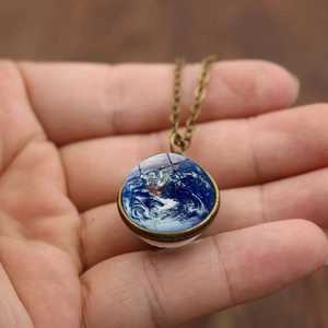 Detail of hand holding a bronze globe pendant necklace with double-sided crystal glass ball