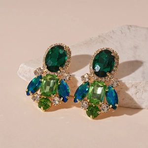 Macro detail of vintage gold earrings with emerald green and navy blue crystals