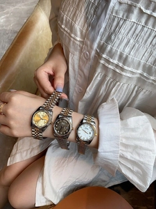 Three two-tone women's watches with rose gold accents and date display on a wrist