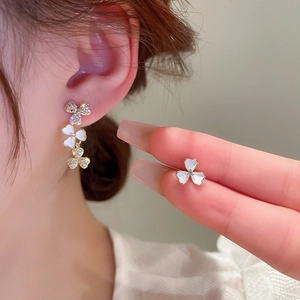 Detail of gold floral dangle earrings with zircon pavé and white clover petal inlays