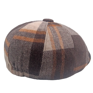 Détail de la texture en laine à carreaux vintage et du bouton sur une casquette gavroche