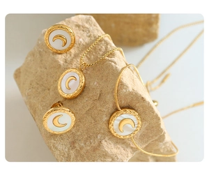 Detailed view of gold plated jewelry set with crescent moon and white shell inlays