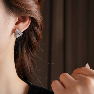 Gros plan d'un mannequin portant des boucles d'oreilles triangulaires en zircon argenté