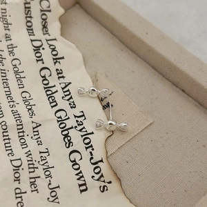 Macro shot of silver candy-shaped stud earrings on a vintage paper and jewelry box