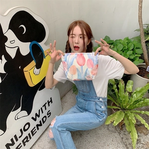 Detailed view of floral cotton makeup bag with tulip print held by model hand