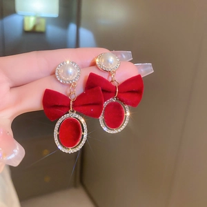 Dettaglio di orecchini a fiocco in velluto rosso con perle e strass per le feste