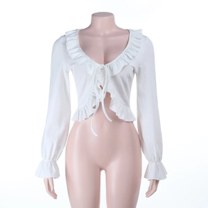 Détail d'un cardigan blanc en maille côtelée avec volants, manches évasées et lien à nouer
