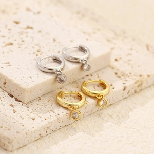 Detailed macro view of gold and silver S925 sterling silver hoop earrings with clear cubic zirconia