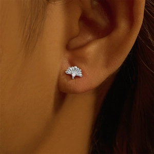 Close-up of fan-shaped silver stud earring with clear gemstone on earlobe