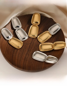 Close-up of geometric rectangle pendant earrings in polished gold and silver finishes