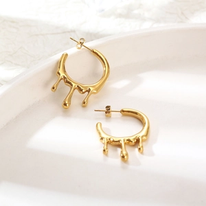 Minimalist gold molten lava drop earrings in liquid fluid design on white ceramic tray