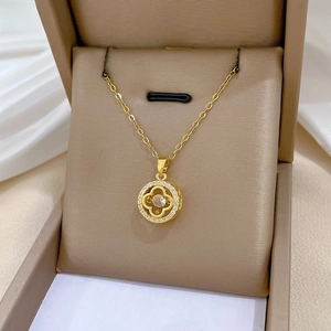 Close-up of gold clover pendant with sparkling pavé crystals in a luxury jewelry box