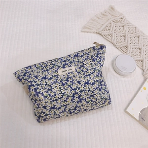 Detailed close-up of blue floral cotton makeup bag with simple wish label on white fabric