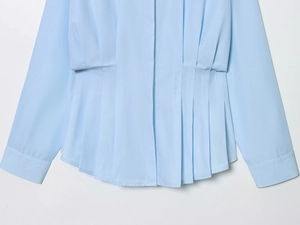 Detail of light blue shirt featuring cinched waist and pleated design for a slim silhouette