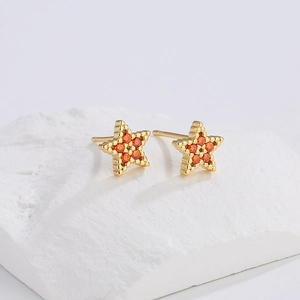 Minimalist 18K gold star stud earrings with orange zircon stones on white stone