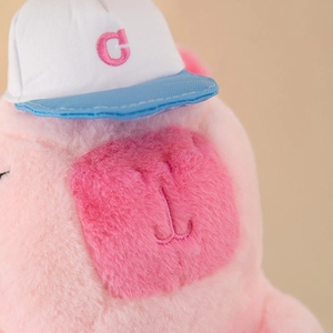 Close-up of pink Capybara plush backpack with embroidered C letter on baseball cap