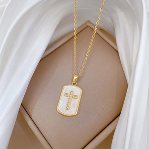 Macro shot of gold-plated shell pendant with crystal cross inlay in jewelry box