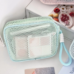 Mint green mesh cosmetic bag with thick honeycomb material and a blue carry handle