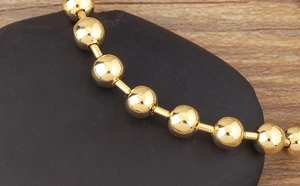 Macro shot of 18k gold plated bead bracelet on black stones with smooth metallic finish