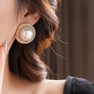 Gros plan de boucles d'oreilles perles vintage avec bords texturés or et argent