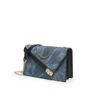Detailed macro view of the denim blue square bag featuring a gold buckle and chain strap