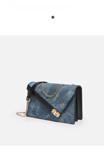 Detailed macro view of the denim blue square bag featuring a gold buckle and chain strap