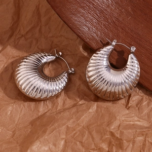 Macro shot of silver textured thick hoop earrings with retro croissant design detail