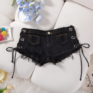 Dettaglio di hot pants in denim nero con bordi sfrangiati, occhielli in metallo e lacci laterali