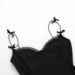 Détail des bretelles à nœuds et de la bordure en dentelle sur une robe noire ajustée
