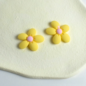 Detailed close-up of yellow resin peach blossom accessory with matte texture on cream board