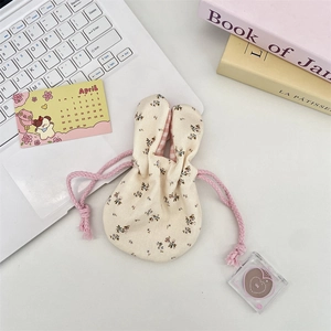 Close-up of floral drawstring bag with rabbit ears and pink checkered lining on a white desk