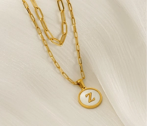Détail du collier doré à deux couches avec un pendentif en nacre et la lettre Z