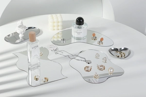Macro shot of irregular acrylic mirror trays with jewelry reflecting on a white desk