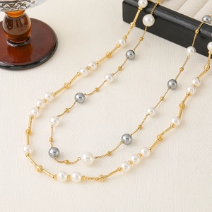 Long multilayer necklace with white and grey pearls on a gold chain, elegant jewelry style