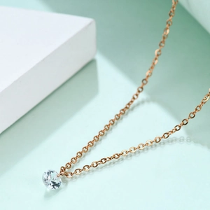 Macro detail of a 6mm round crystal solitaire pendant on a rose gold clavicle chain